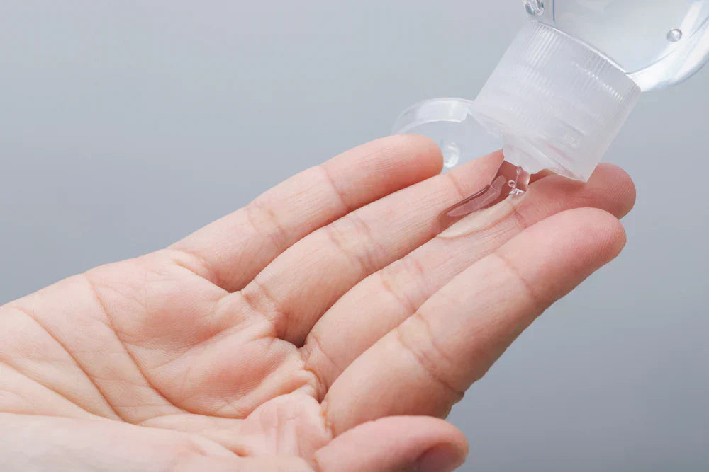 A hand holding a small amount of gel cleanser, with the bottle dispensing the product.