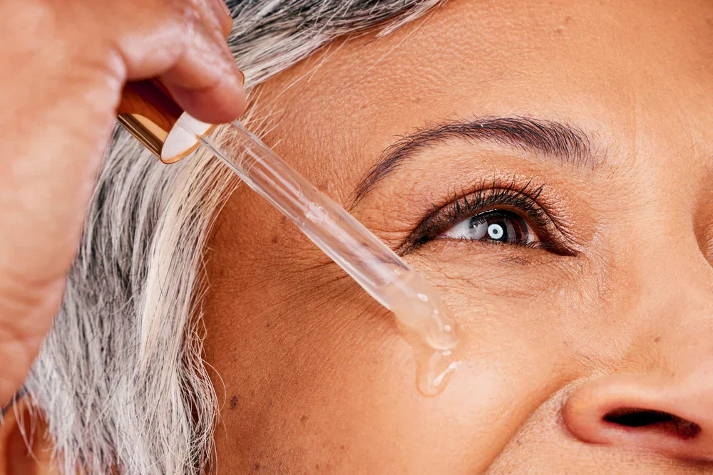 A woman applying retinol serum to her under-eye area using a dropper, highlighting the use of retinol for skincare.